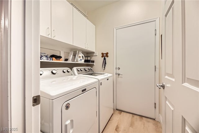 washroom with light hardwood / wood-style floors, cabinets, and washing machine and clothes dryer