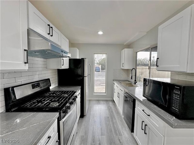 kitchen featuring sink, light hardwood / wood-style flooring, black appliances, white cabinets, and decorative backsplash