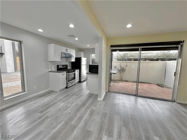 kitchen with decorative backsplash, stainless steel appliances, white cabinets, and light wood-type flooring