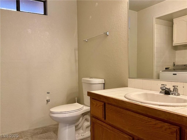 bathroom with vanity, toilet, washer / clothes dryer, and tasteful backsplash