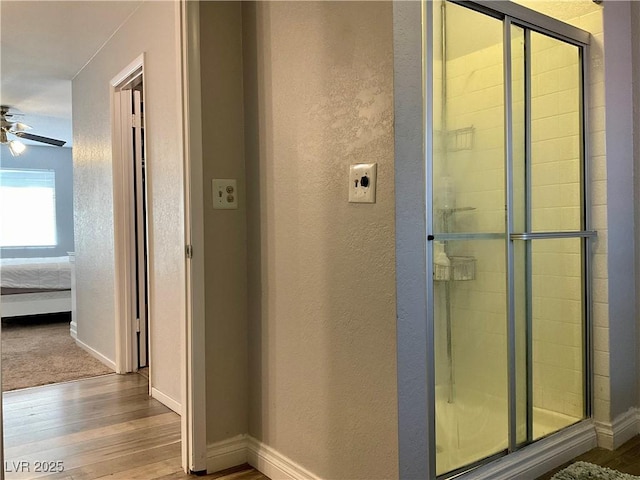 bathroom with ceiling fan, wood-type flooring, and a shower with door