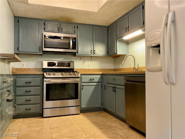 kitchen with sink, light tile patterned floors, and stainless steel appliances