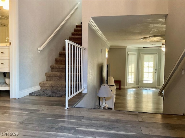 staircase featuring hardwood / wood-style floors, ceiling fan, and crown molding