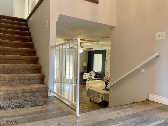 stairway featuring hardwood / wood-style flooring, ceiling fan, and ornamental molding