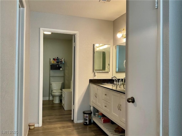 bathroom with hardwood / wood-style floors, vanity, and toilet