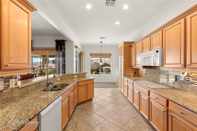 kitchen featuring sink, pendant lighting, white appliances, light stone countertops, and backsplash