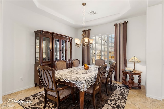 dining space with light tile patterned floors, a tray ceiling, and a chandelier