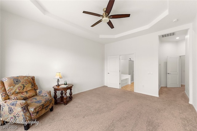 sitting room featuring light carpet, a tray ceiling, and ceiling fan