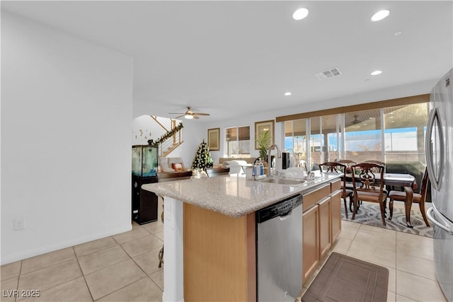 kitchen featuring a wealth of natural light, stainless steel appliances, ceiling fan, sink, and an island with sink