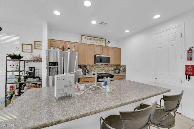 kitchen with tasteful backsplash, a breakfast bar area, light tile patterned flooring, and appliances with stainless steel finishes