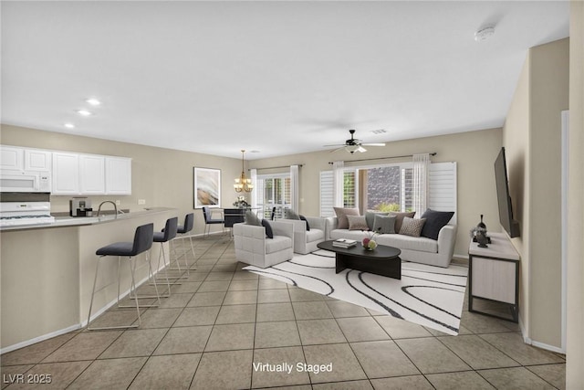 tiled living room featuring sink and ceiling fan with notable chandelier