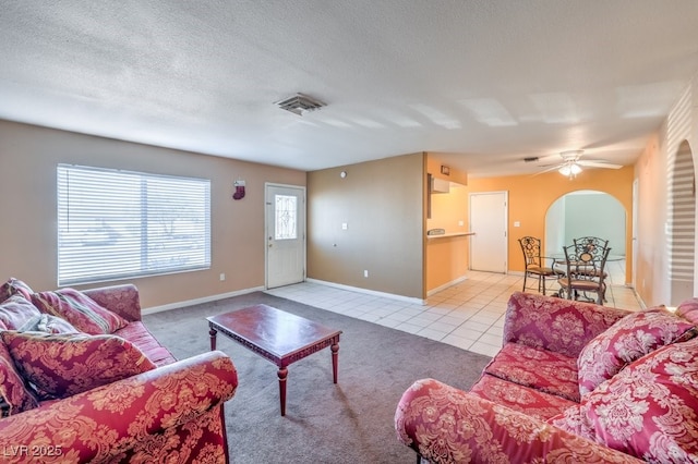 living room with a textured ceiling, ceiling fan, and light tile patterned flooring