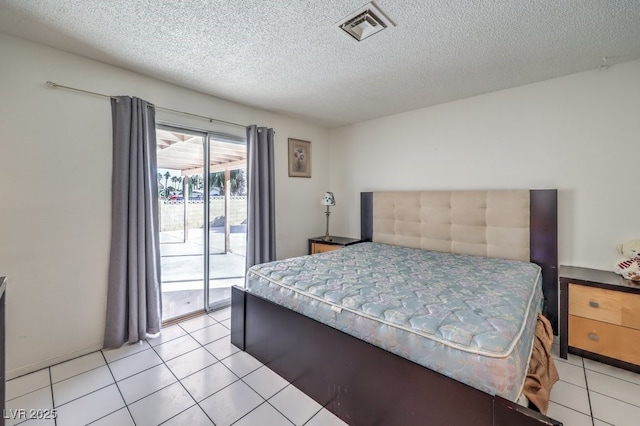 bedroom with light tile patterned floors, a textured ceiling, and access to outside