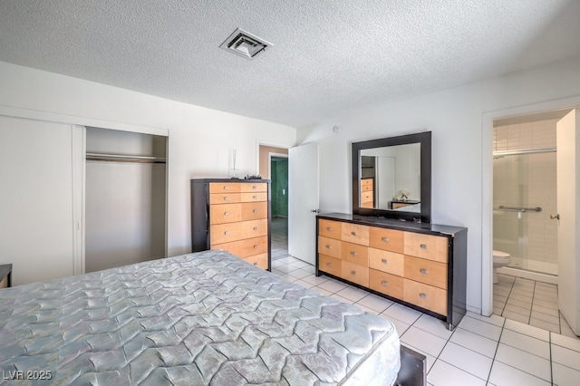 tiled bedroom featuring ensuite bathroom, a textured ceiling, and a closet