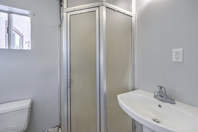 bathroom featuring toilet, an enclosed shower, and sink