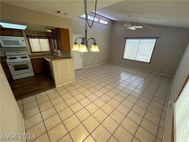 kitchen featuring a textured ceiling, white appliances, pendant lighting, and light tile patterned flooring