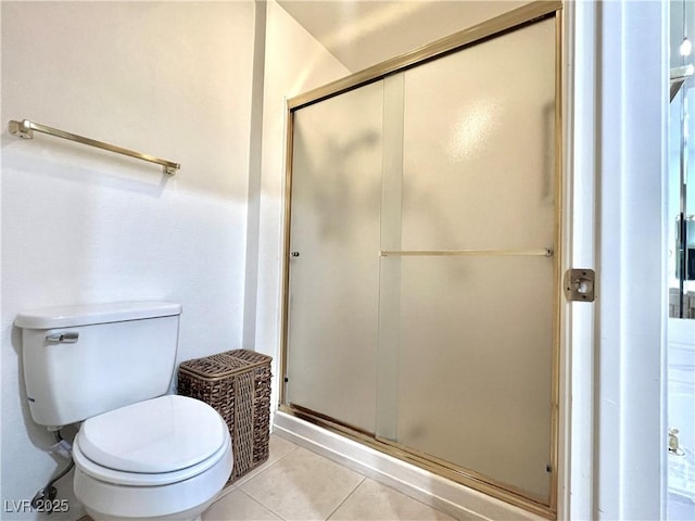 bathroom featuring tile patterned flooring, toilet, and a shower with door