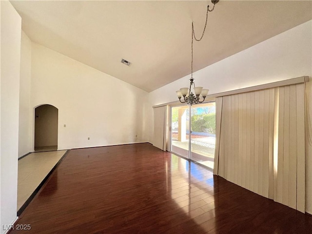 unfurnished living room featuring dark hardwood / wood-style flooring, vaulted ceiling, and an inviting chandelier