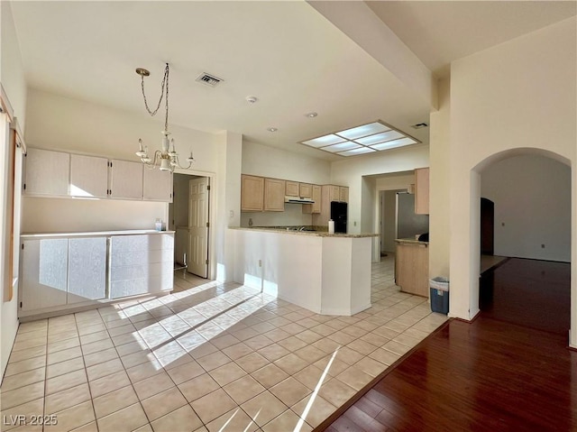 3012 Morning Ridge Dr, Las Vegas, NV 89134 - kitchen with arched walkways, a chandelier, under cabinet range hood, pendant lighting, and light tile patterned floors