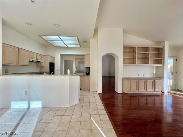 kitchen featuring kitchen peninsula, stainless steel fridge, light stone counters, light tile patterned floors, and light brown cabinets