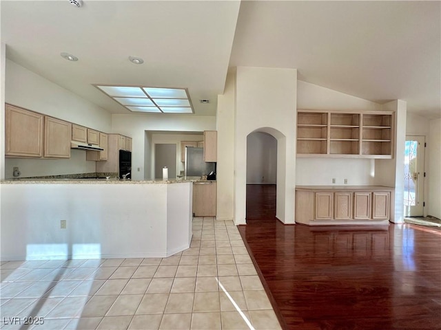 3012 Morning Ridge Dr, Las Vegas, NV 89134 - kitchen featuring under cabinet range hood, light brown cabinets, arched walkways, light wood-style floors, and a peninsula