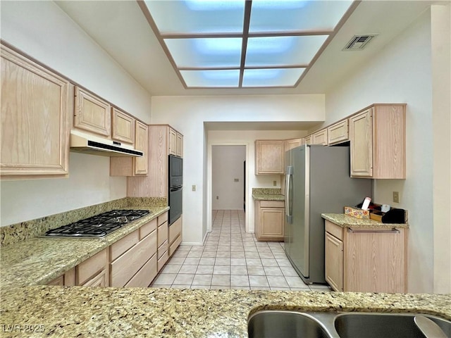 3012 Morning Ridge Dr, Las Vegas, NV 89134 - kitchen with light brown cabinetry, appliances with stainless steel finishes, under cabinet range hood, light tile patterned flooring, and light stone countertops