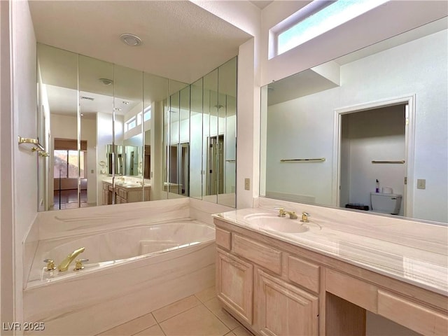 bathroom featuring tile patterned floors, vanity, a tub to relax in, and toilet