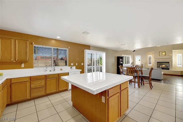 kitchen with sink, a center island, tile countertops, and light tile patterned flooring