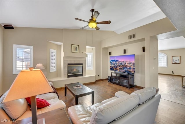 living room with a fireplace, hardwood / wood-style floors, ceiling fan, and vaulted ceiling