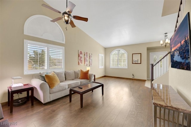 living room with ceiling fan with notable chandelier, high vaulted ceiling, and dark wood-type flooring