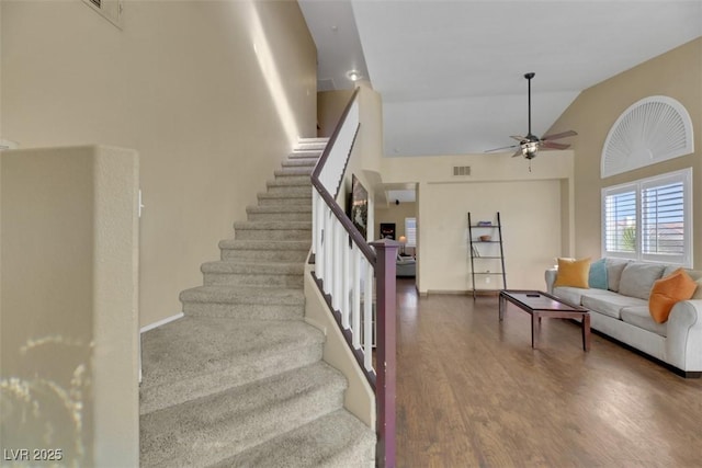 staircase with ceiling fan, wood-type flooring, and lofted ceiling