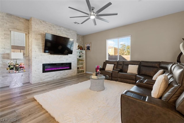 living room featuring a large fireplace, ceiling fan, and light hardwood / wood-style floors