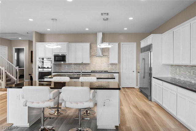 kitchen featuring a center island with sink, built in appliances, and pendant lighting