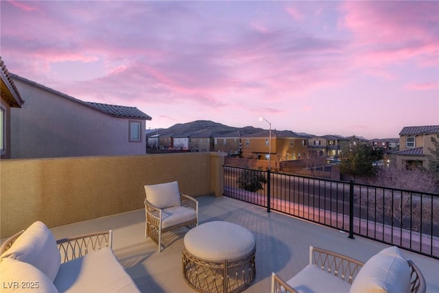 patio terrace at dusk featuring a balcony, a mountain view, and outdoor lounge area