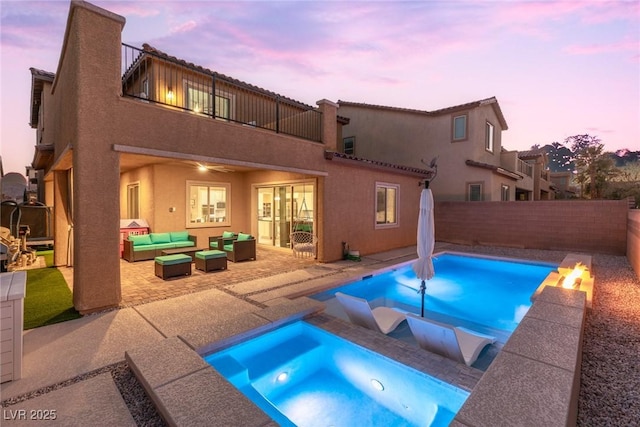 pool at dusk with an in ground hot tub, a patio area, and outdoor lounge area