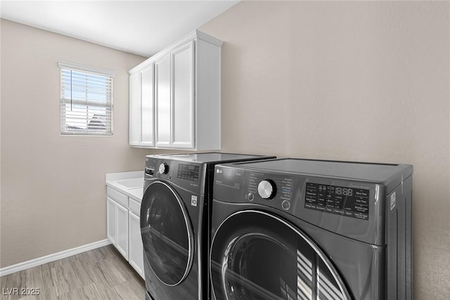 laundry area featuring cabinets, washing machine and dryer, and light wood-type flooring