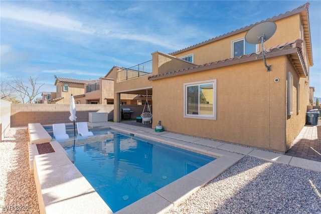 rear view of house featuring a patio and a fenced in pool