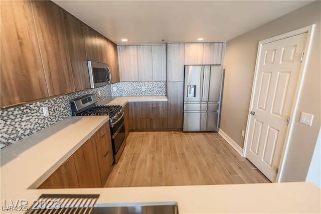 kitchen featuring backsplash, stainless steel appliances, and light wood-type flooring