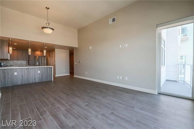 kitchen with tasteful backsplash, pendant lighting, dark wood-type flooring, and stainless steel refrigerator with ice dispenser