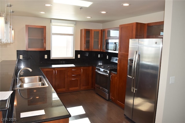 kitchen featuring sink, dark hardwood / wood-style flooring, backsplash, pendant lighting, and appliances with stainless steel finishes