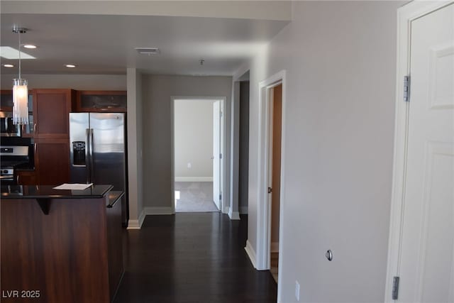 kitchen featuring decorative light fixtures, a kitchen bar, dark wood-type flooring, and appliances with stainless steel finishes