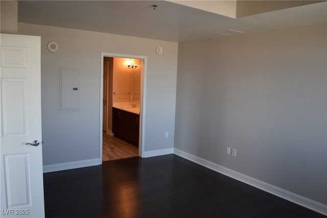 spare room with dark hardwood / wood-style flooring, sink, and electric panel