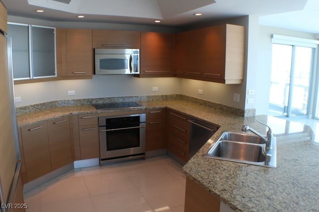 kitchen with light stone countertops, sink, stainless steel appliances, kitchen peninsula, and light tile patterned floors