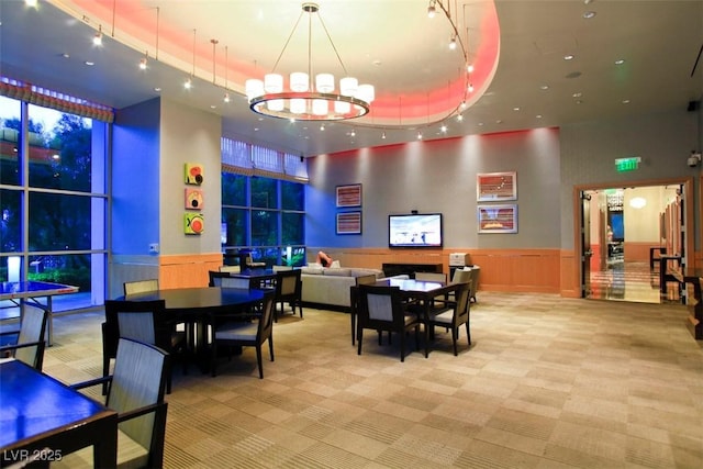 recreation room with a chandelier, a towering ceiling, and light colored carpet