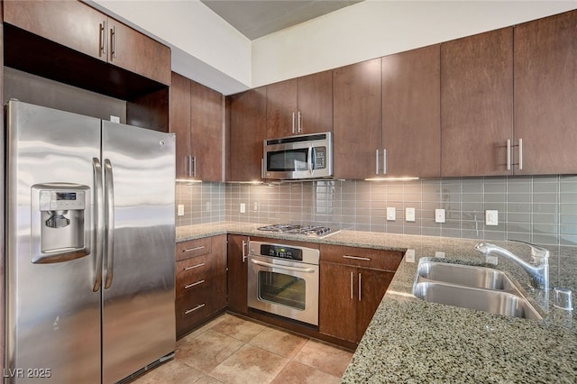 kitchen featuring backsplash, light stone counters, sink, and stainless steel appliances