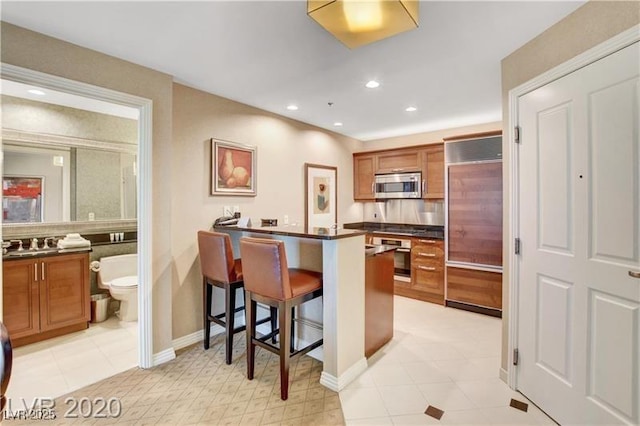 kitchen featuring a kitchen bar, light tile patterned floors, and stainless steel appliances