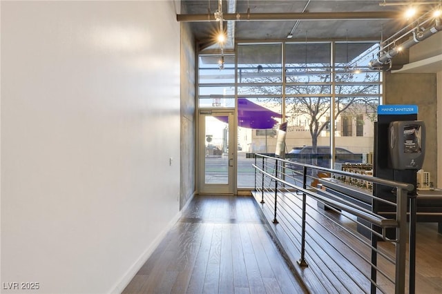 hall featuring wood-type flooring, a towering ceiling, and expansive windows