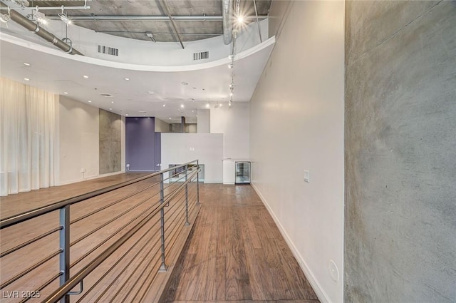 hallway with wine cooler, hardwood / wood-style floors, and a towering ceiling