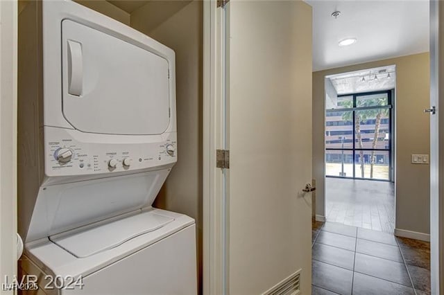 laundry room with tile patterned flooring and stacked washing maching and dryer