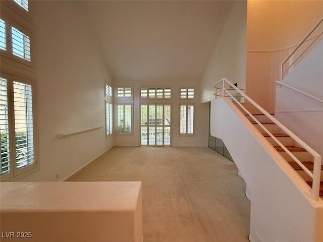 unfurnished living room with plenty of natural light, carpet floors, and a towering ceiling